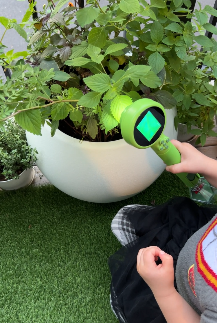child holding the Leuoa digital microscope to examine a plant