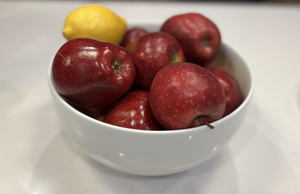A bowl containing six Red Delicious apples and one large lemon, the primary ingredients for this sugar-free applesauce experiment.